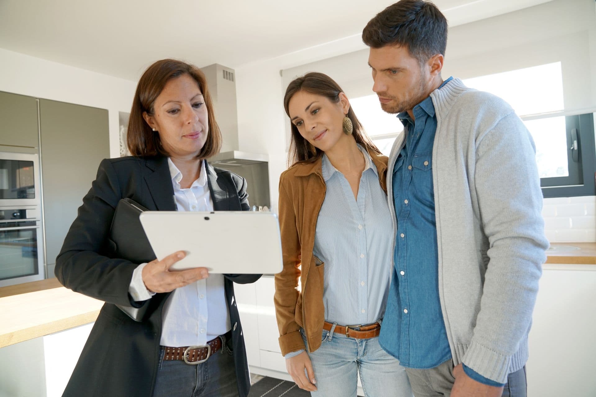 Couple with sales agent visiting house and discussing options.